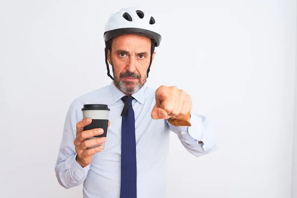 Middle age businessman wearing bike helmet drinking coffee over isolated white background pointing with finger to the camera and to you, hand sign, positive and confident gesture from the front