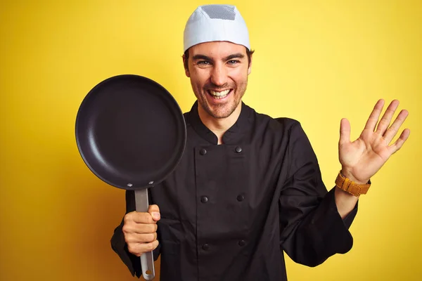年轻厨师身穿制服 头戴礼帽 把锅盖在孤立的黄色背景上 非常高兴而兴奋 获奖者面带微笑地欢呼胜利 举起双手庆祝胜利 — 图库照片