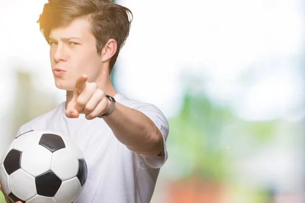 Junger Mann Hält Fußballball Über Isoliertem Hintergrund Und Zeigt Mit — Stockfoto