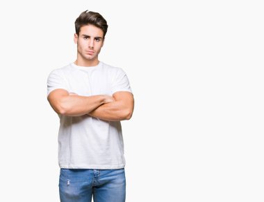İzole arka plan şüpheci ve sinir, onaylamayan ifade yüz çapraz kolları üzerinde beyaz t-shirt giyen genç yakışıklı adam. Negatif kişi.