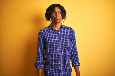 Rastgele tişörtlü Afro adam izole edilmiş sarı arka planda duruyor dudaklı balık suratı yapıyor, çılgınca ve komik bir jest. Komik ifade.