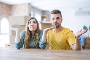Masada oturan genç çift yeni evlerine taşınıyor. Arkalarında karton kutular ve kolları ve elleri havada, kafası karışık bir ifade var. Şüphe kavramı.