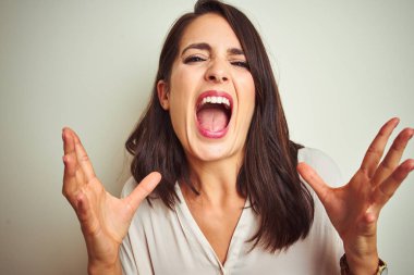 Genç ve güzel bir kadın, izole edilmiş beyaz arka plan üzerinde dikilmiş kızgın ve çılgın bir şekilde bağırıyor ve agresif bir ifade ve kollarla bağırıyor. Hayal kırıklığı konsepti.
