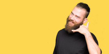 Genç sarışın adam rahat t-shirt giyen gülümseyen el ve parmak telefonda konuşmak ile telefon jest yapıyor. Kavramları iletişim.