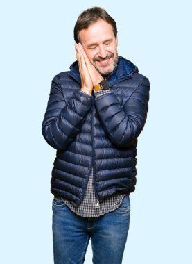 Orta yaş yakışıklı adamın kış ceket uyku giydiğini hayal ve elleri ile kapalı gözler gülümseyen birlikte poz yorgun.