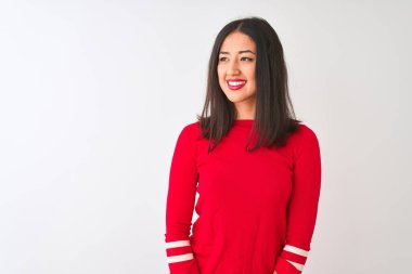 İzole edilmiş beyaz arka planda duran kırmızı elbiseli genç, güzel Çinli kadın yüzünde gülümsemeyle, doğal bir ifadeyle yan yana bakıyor. Kendinden emin gülen.