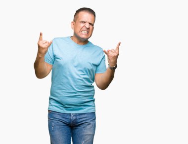 Orta yaş Arap adam deli ifade rock simge elle yapıyor ile bağırarak izole arka plan üzerinde mavi tişört giyiyor. Müzik yıldızı. Ağır kavramı.