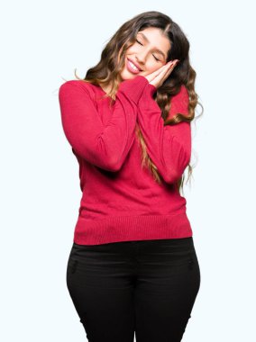 Rüya ve elleri ile kapalı gözler gülümseyen birlikte poz kırmızı kazaklı uyku giyen genç güzel kadın yorgun.