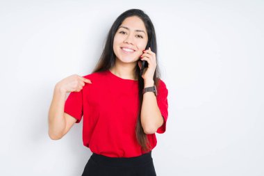 Akıllı telefondan konuşan genç esmer kadın izole bir arka planda kendini işaret eden şaşkın bir yüzle.