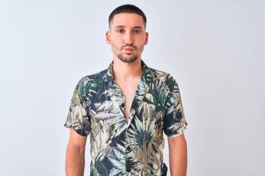 Young handsome man wearing Hawaiian summer shirt over isolated background puffing cheeks with funny face. Mouth inflated with air, crazy expression.