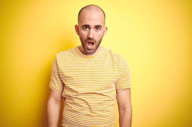 Sakallı, sarı renkli tişörtlü genç, kel bir adam. Şok olmuş, ağzı açık, alaycı ve şüpheci görünüyor.