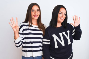 İzole edilmiş beyaz arka planda dikilen gündelik giysiler giyen genç ve güzel kadınlar dokuz numaralı parmaklarıyla işaret ederken kendinden emin ve mutlu bir şekilde gülümsüyor..