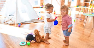 Anaokulunda bir sürü oyuncakla oynayan sevimli çocuklar.