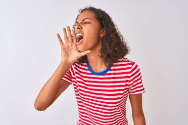 Kırmızı çizgili tişört giyen genç Brezilyalı kadın izole edilmiş beyaz arka planda durup el ele tutuşarak bağırıyor ve çığlık atıyordu. İletişim konsepti.