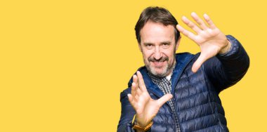 Orta yaş yakışıklı adam çerçeve kullanarak yapıyor gülen eller avuç içi ve parmaklar, kamera perspektif kış palto giyiyor