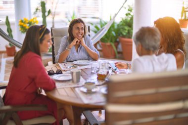 Genç ve güzel bir kız mutlu ve kendinden emin bir şekilde terasta oturmuş bir fincan kahve içiyor.
