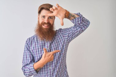 Genç kızıl İrlandalı adam rahat gömlek giyerek izole beyaz arka plan üzerinde duran gülümseyerek mutlu yüzü ile elleri ve parmakları ile çerçeve yapma. Yaratıcılık ve fotoğrafçılık konsepti.