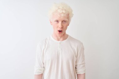 Genç albino tişörtlü sarışın adam izole edilmiş beyaz arka planda duruyor korku, korku ve heyecan dolu bir yüz ifadesinden korkuyor ve şoka uğruyor..