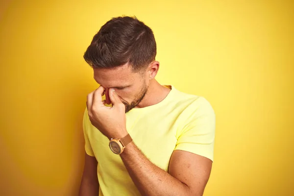 年轻英俊的男子穿着休闲的黄色T恤 背对着黄色孤立的背景 疲倦地揉揉鼻子和眼睛 感到疲倦和头痛 压力和挫败感概念 — 图库照片