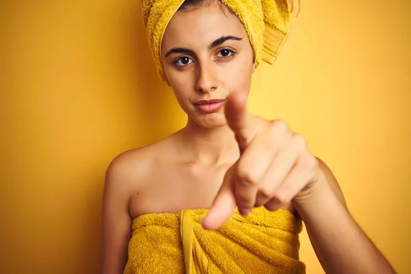 Young beautiful woman wearing a towel over yellow isolated background pointing with finger to the camera and to you, hand sign, positive and confident gesture from the front