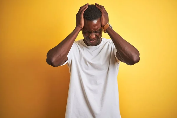年轻的非洲裔美国男人穿着白色的T恤 站在孤立的黄色背景之上 因疼痛和偏头痛而感到绝望和压力 手放在头上 — 图库照片