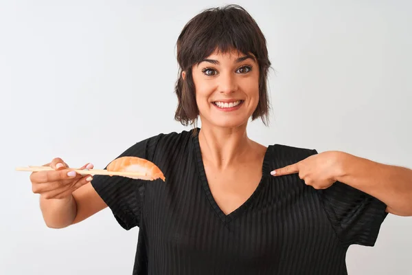 Beautiful woman eating salmon nigiri sushi using chopsticks over isolated white background with surprise face pointing finger to himself