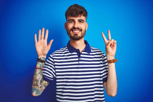Mladý Muž Tetováním Sobě Pruhované Pólo Stojící Nad Izolované Modré — Stock fotografie