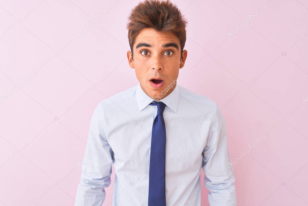 Young handsome businessman wearing shirt and tie standing over isolated pink background afraid and shocked with surprise and amazed expression, fear and excited face.