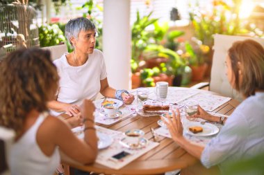 Genç ve güzel bir kız mutlu ve kendinden emin bir şekilde terasta oturmuş bir fincan kahve içiyor.