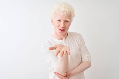 Genç albino sarışın adam, gündelik tişört giyip izole edilmiş beyaz arka planda dikiliyor ve kameraya bakıp havada öpücükler savuruyor. Güzel ve seksi. Aşk ifadesi.