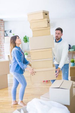 Genç güzel çift yeni evde karton kutu yığını tutan