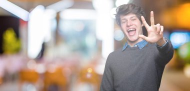 Genç yakışıklı zarif adam gösterilen ve parmakları ile işaret izole arka plan üzerinde üçüncü ise kendinden emin ve mutlu gülümseyerek.