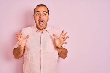 Soyutlanmış pembe arka planda duran zarif gömlekli genç adam çılgın ve başarıyı kollarını kaldırıp heyecanla haykırarak kutluyor. Kazanan konsept