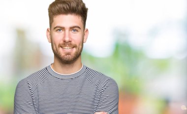 Yakışıklı delikanlı giyen kazak mutlu yüz çapraz silah kameraya bakarak ile gülümseyen çizgili. Olumlu bir kişi.