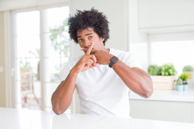 Beyaz tişört giyen genç Afro-Amerikalı adam evde oturuyor. Reddedilme ifadesi negatif işaret veriyor.