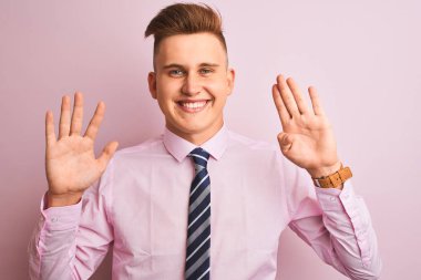 Genç yakışıklı işadamı gömlek ve kravat izole pembe arka plan üzerinde duran gösteren ve parmakları ile işaret ederken emin ve mutlu gülümsüyor.