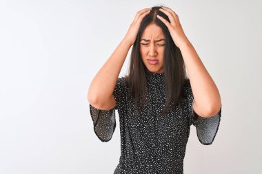 Zarif tişörtler giyen genç Çinli bir kadın izole edilmiş beyaz arka planda duruyor. Ağrı ve migren yüzünden baş ağrısı ve stresten muzdarip. Ellerini başının üstüne koy..