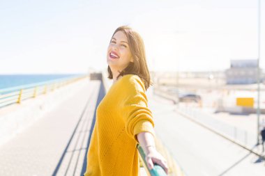 Güzel genç kadın kapalı gözleri ile gülümseyen ve açık silah güneşli bir gün güneş ışığı zevk. Mutlu güneşlenmek