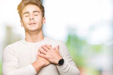 Yakışıklı delikanlı ile gülümseyen izole arka plan üzerinde kapalı gözler ve yüzünde minnettar jest ile göğüs üzerinde eller. Sağlık kavramı.