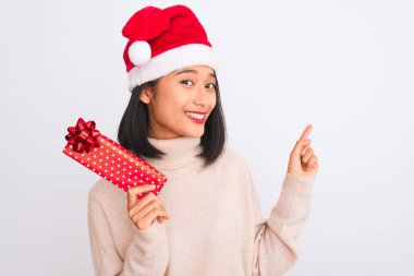 İzole edilmiş beyaz arka plan üzerinde eldiven tutan genç Çinli temizlikçi kadın mutlu bir şekilde elini ve parmağını kenarı işaret ediyor.