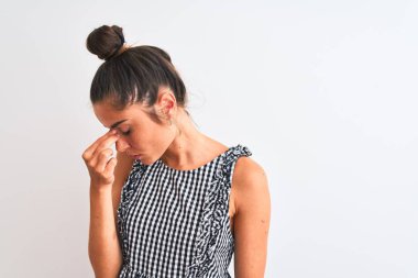 Çörek giymiş güzel bir kadın izole edilmiş beyaz arka planda dikilmiş yorgun burnu ve gözleri ovuşturarak yorgunluk ve baş ağrısı hissediyor. Stres ve hüsran kavramı.