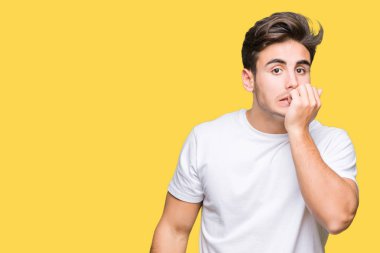 Genç yakışıklı adam stresli ve gergin ile izole arka plan üzerinde beyaz t-shirt giyen tırnak ısırma dudaklarından eller. Anksiyete sorunu.