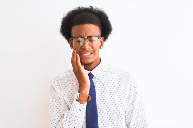 Genç Afro-Amerikalı iş adamı, diş ağrısı ya da diş ağrısı yüzünden izole edilmiş beyaz arka plan üzerinde kravat ve gözlük takıyor ve ağza acı dolu bir ifadeyle dokunuyor. Dişçi konsepti.