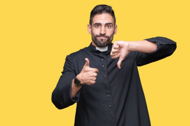 Genç Hıristiyan anlaşmazlık ve anlaşma ifade izole arka plan üzerinde yapıyor başparmak yukarı ve aşağı, rahip. Deli çatışma