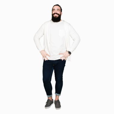 Uzun saçlı ve sakal giyen sportif sweatshirt, yüzünde gülümseme ile yan bakmak, doğal ifade ile genç adam. Güven gülüyor.