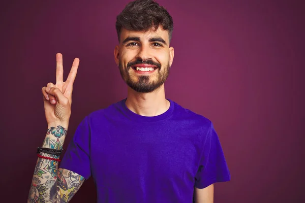Mladý Muž Tetováním Tričkem Stojící Nad Izolovaným Fialovým Pozadím Ukazující — Stock fotografie