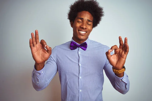 穿着条纹衬衫和紫色领结的非洲商人在孤立的白色背景上放松 闭上双眼微笑 用手指做冥想动作 瑜伽概念 — 图库照片