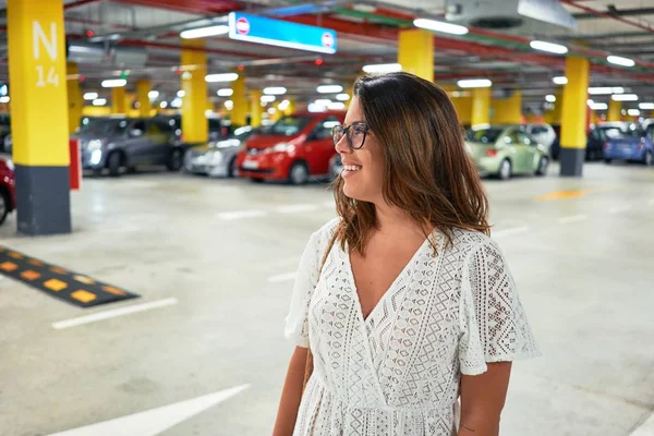 車やライトの周りの地下駐車場で自信を笑顔若い女性 — ストック写真