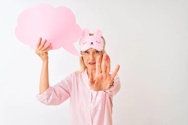 Middle age woman wearing sleep mask holding speech bubble over isolated white background with open hand doing stop sign with serious and confident expression, defense gesture