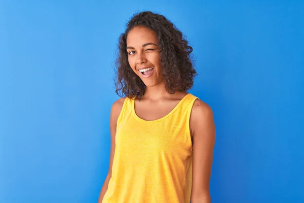 Jovem Brasileira Vestindo Camiseta Amarela Sobre Fundo Azul Isolado Piscando — Fotografia de Stock